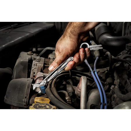 Action shot of a mechanic's grease-covered hand using a 14mm ratcheting wrench to tighten a bolt within a car engine bay.