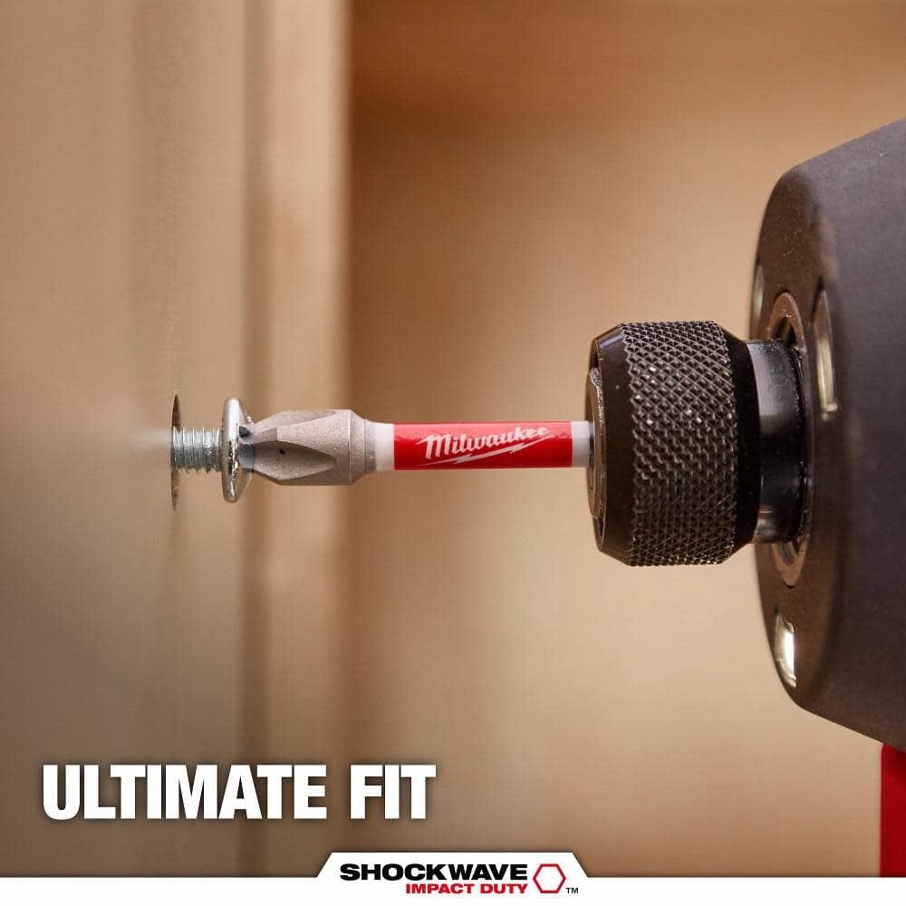 A close-up action shot of a silver Milwaukee SHOCKWAVE Phillips bit driving a screw into a neutral-colored interior wall, showcasing the ultimate fit of the Wear Guard Tip.