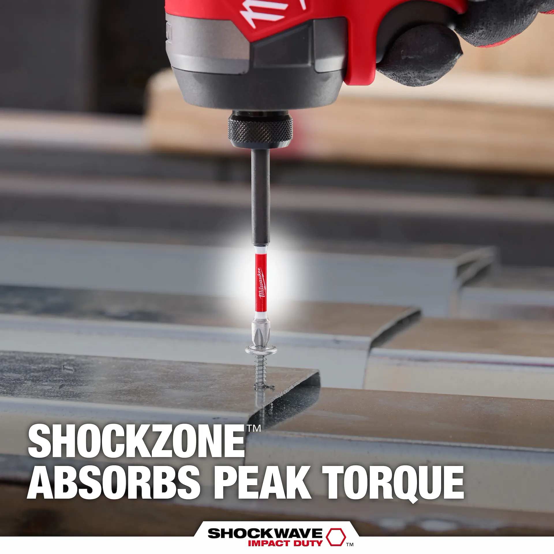 An action shot demonstrating the torque-absorbing Shockzone of a Milwaukee SHOCKWAVE power bit as it drives a screw into a metal track, highlighting its high-torque durability.