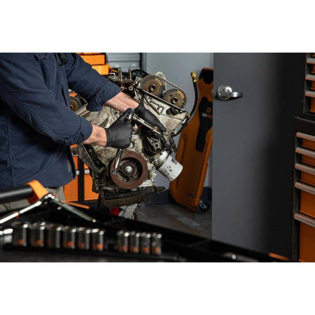 An action photo of a technician using a GEARWRENCH 1/2 inch drive socket and ratchet to perform maintenance on a vehicle engine, illustrating the tool's use in professional mechanical work.
