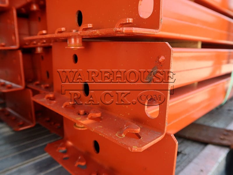 A detailed close-up shot of the universal teardrop shaved-pin end connectors and safety locking pins on the end of a high-capacity 5 15/16-inch face orange industrial load beam.