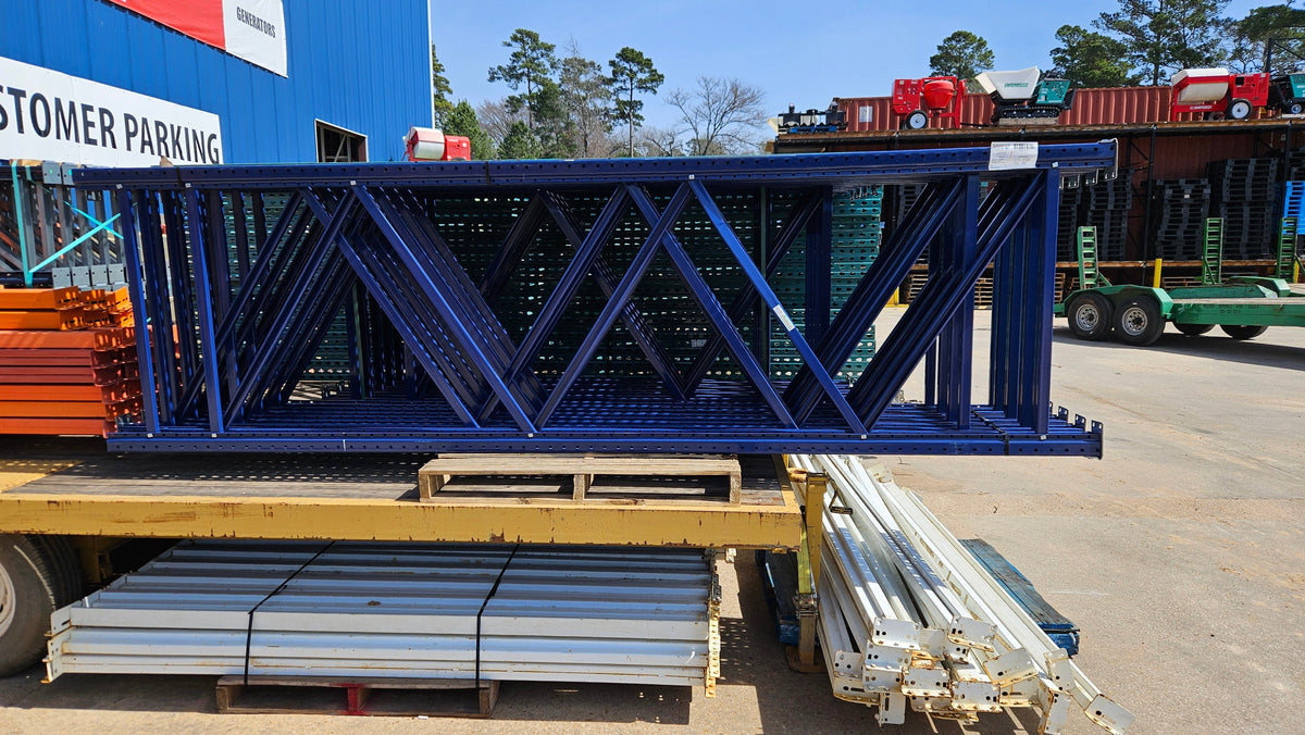 A wide side-profile view of a UPTD14424291RN industrial blue teardrop pallet rack upright frame resting on a transport trailer, highlighting the 144-inch height and 24-inch depth with reinforced steel bracing for warehouse storage.