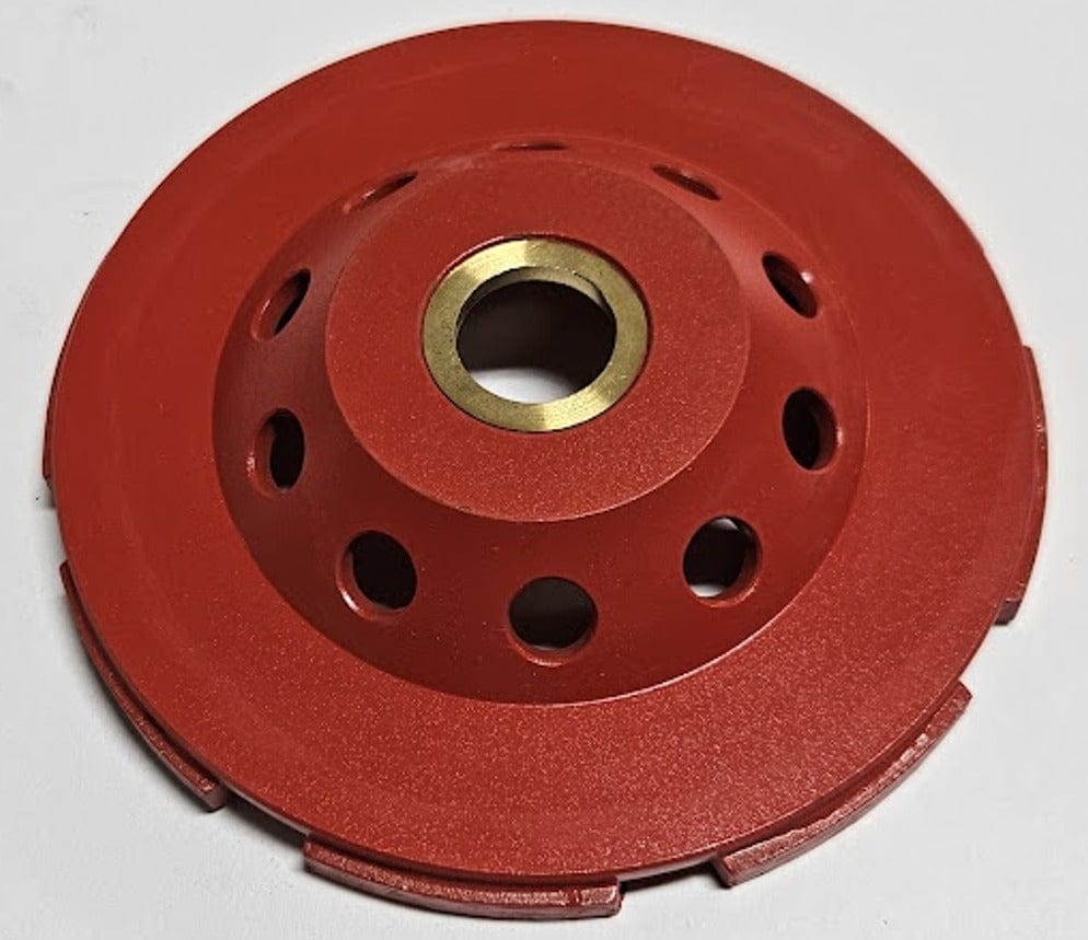 The reverse side of the OX Tools 4-inch diamond cup grinding disc showing the red powder-coated steel housing with integrated cooling holes and a 7/8 inch arbor for standard angle grinder attachment.