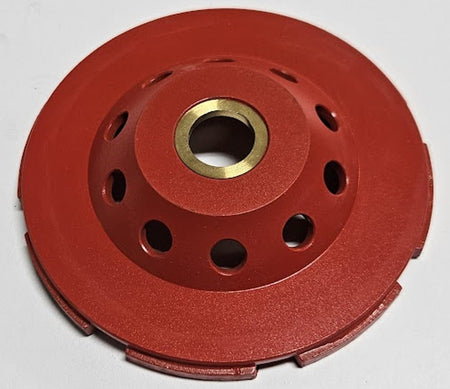 The reverse side of the OX Tools 4-inch diamond cup grinding disc showing the red powder-coated steel housing with integrated cooling holes and a 7/8 inch arbor for standard angle grinder attachment.