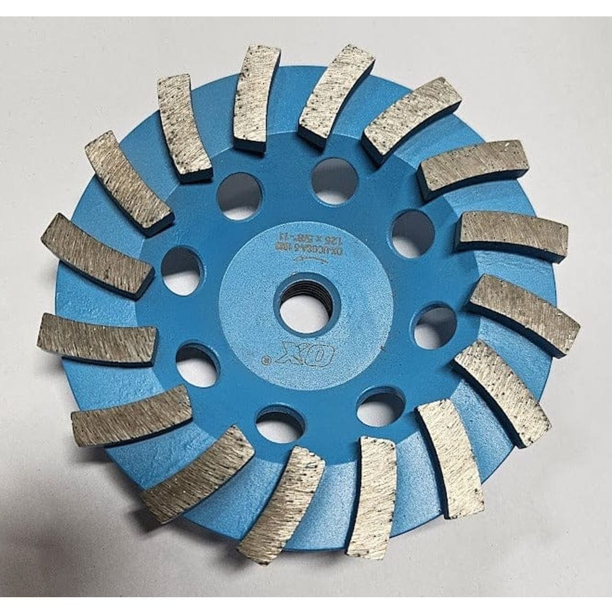 A top-down view of the OX Tools 5-inch single row diamond cup grinder featuring blue steel construction and aggressive spiral-segmented diamond teeth for heavy-duty concrete and stone grinding.