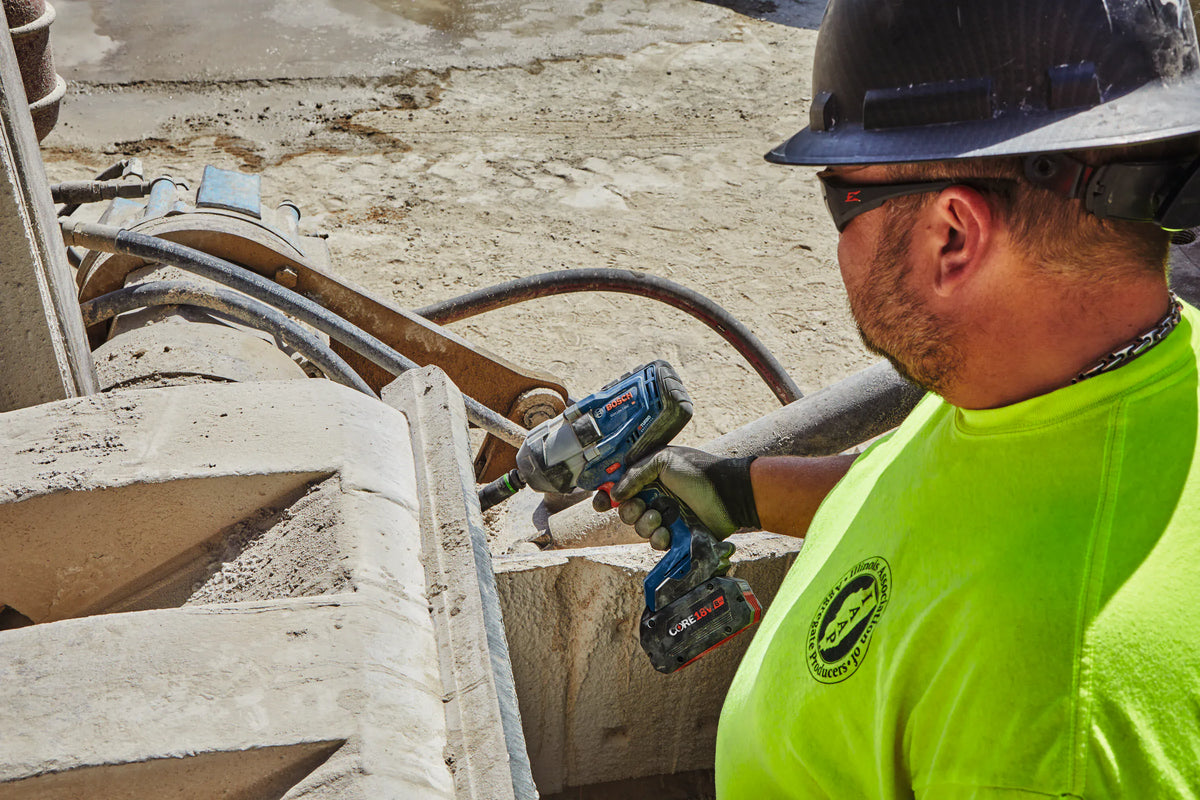 An overhead jobsite application view of an industrial worker using the cordless Bosch PROFACTOR high torque impact wrench to complete a machinery repair task at an aggregate processing facility.