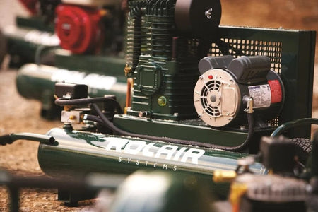 Close-up view of the Rolair 2 HP compressor motor and pump assembly mounted on the green twin tank, highlighting the pump's cooling fins and the electric motor