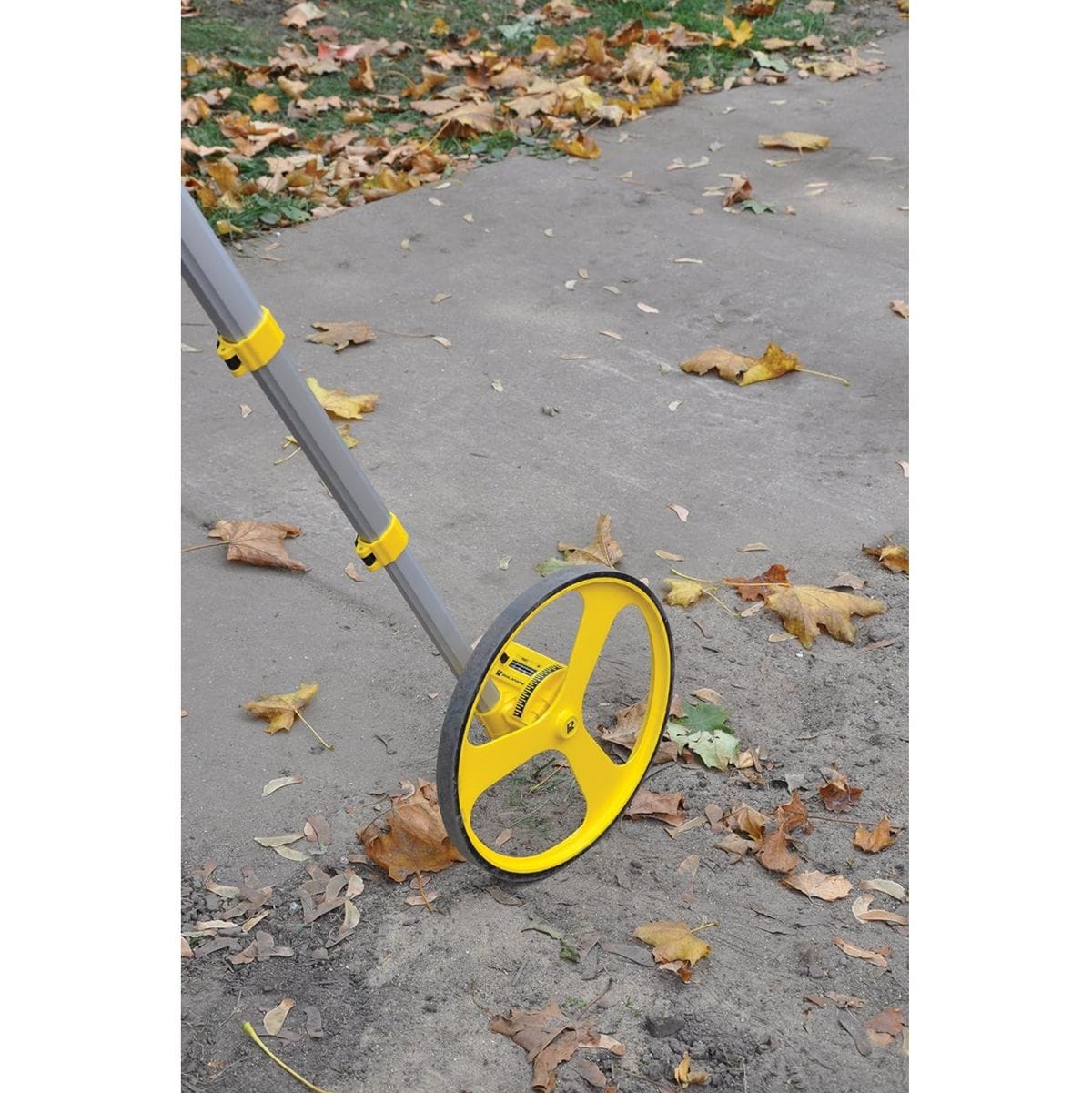 Rolatape RT312M measuring wheel rolling across concrete and dirt ground to calculate metric distance survey measurements.