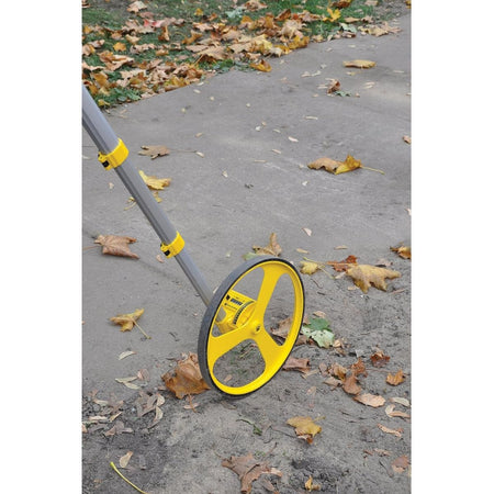 Rolatape RT312M measuring wheel rolling across concrete and dirt ground to calculate metric distance survey measurements.
