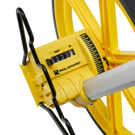 A close-up view of the magnified mechanical counter on the Rolatape RT300 measuring wheel, showing high-visibility digits for feet and inches and a durable axle-drive housing.