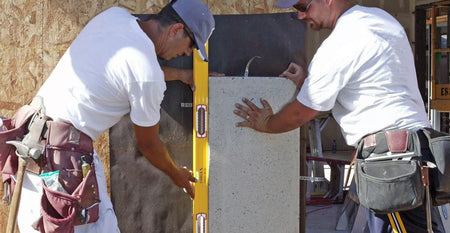 Two workers using the long STABILA level vertically to plumb a concrete form panel during construction.