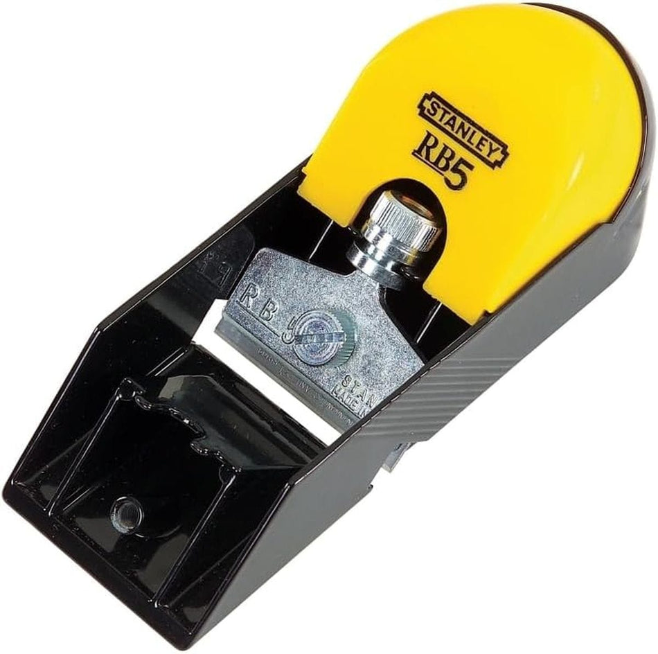 Top-down angled view of a STANLEY 12-105 RB5 manual block hand planer showing the black cast iron bed, steel blade iron assembly with clamping screw, and contoured yellow composite handle for woodworking edge leveling.
