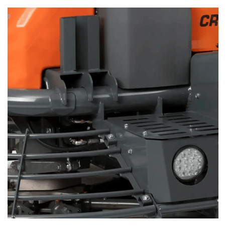 The image shows a close-up view of a Husqvarna 59" Riding Power Trowel CRT 60 74LX. It highlights the machine's features, including the operator's area with the seat, control levers, and handles, along with a portion of the orange fuel tank. The safety cage surrounding the rotating trowel blades is also visible.