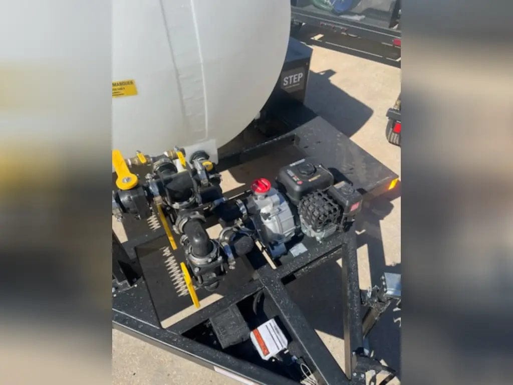 An overhead angled view of the engine-driven pump system on the Simpson water trailer, illustrating the compact and accessible layout of the fuel tank, engine controls, and water intake valves.