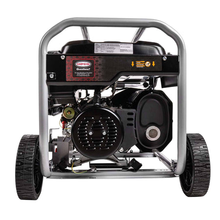 Rear view of the generator showing the silver alternator end cap, black muffler assembly with heat shield, and the wheel axle.