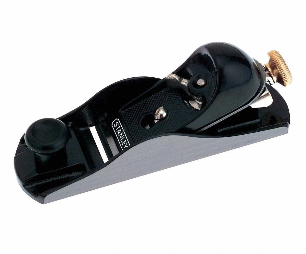 Studio view of the Stanley 12-220 adjustable block plane featuring a black cast iron body with precision ground silver sides, a front finger rest knob, and a brass adjustment wheel at the rear.