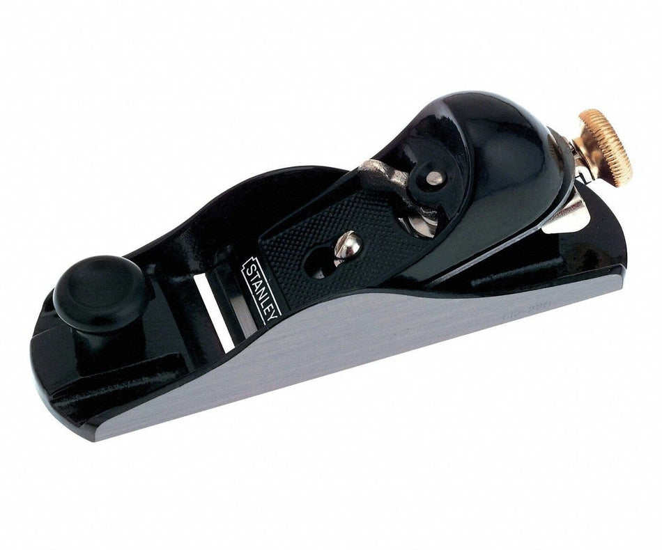 Studio view of the Stanley 12-220 adjustable block plane featuring a black cast iron body with precision ground silver sides, a front finger rest knob, and a brass adjustment wheel at the rear.