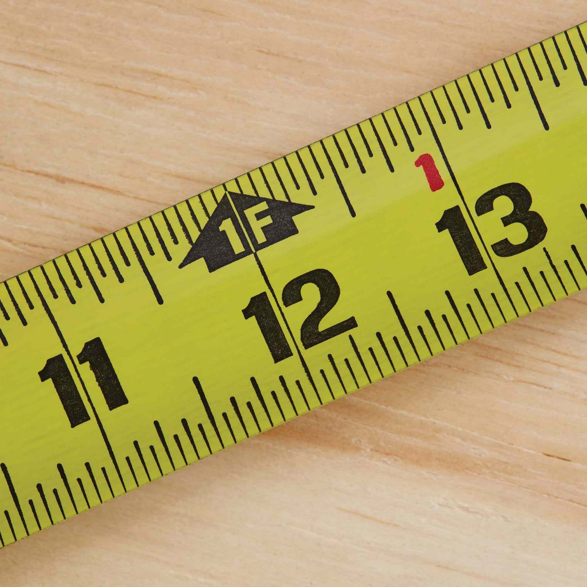 A close-up shot of the Stanley FATMAX tape measure blade at the 12-inch mark, showing the clear 1F (one foot) designation and high-visibility fractional markings for precise jobsite framing measurements.