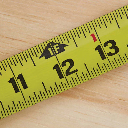 A close-up shot of the Stanley FATMAX tape measure blade at the 12-inch mark, showing the clear 1F (one foot) designation and high-visibility fractional markings for precise jobsite framing measurements.