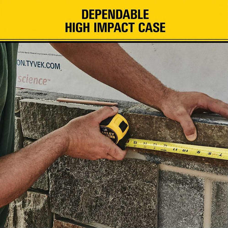 Worker using a Stanley FatMax 16 ft tape measure to measure stonework, demonstrating the tool’s high‑impact case, strong blade standout, and rugged reliability for framing and construction environments.