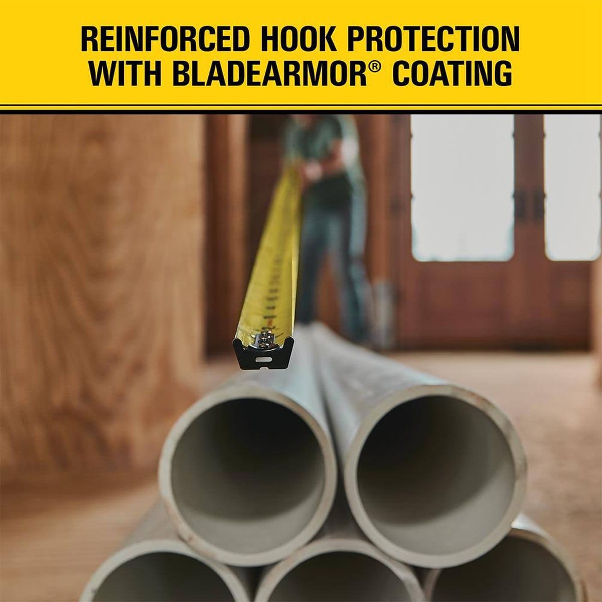 Detailed application shot of the Stanley FATMAX blade extending across stacked PVC pipes, emphasizing the BladeArmor coating and high-visibility measurement markings for professional use.