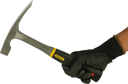 Lifestyle view of a gloved hand gripping the Stanley FatMax brick hammer, demonstrating the ergonomic handle fit and readiness for masonry work.