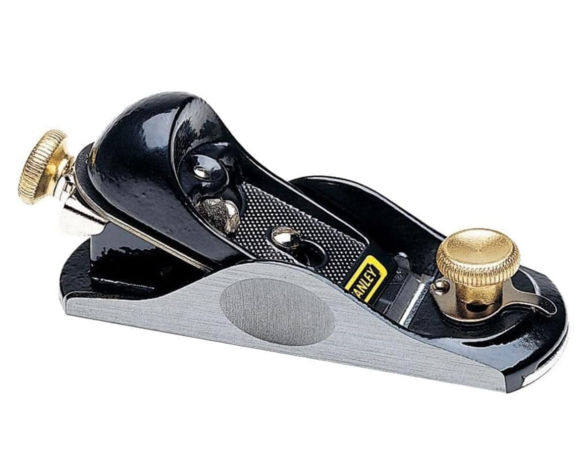 Studio view of the Stanley 12-920 block plane featuring a black cast iron body with precision ground silver sides, brass adjustment knobs, and a quick-release cam lock lever.