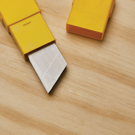 Replacement utility blade partially extended from its yellow protective storage case for quick and safe installation.