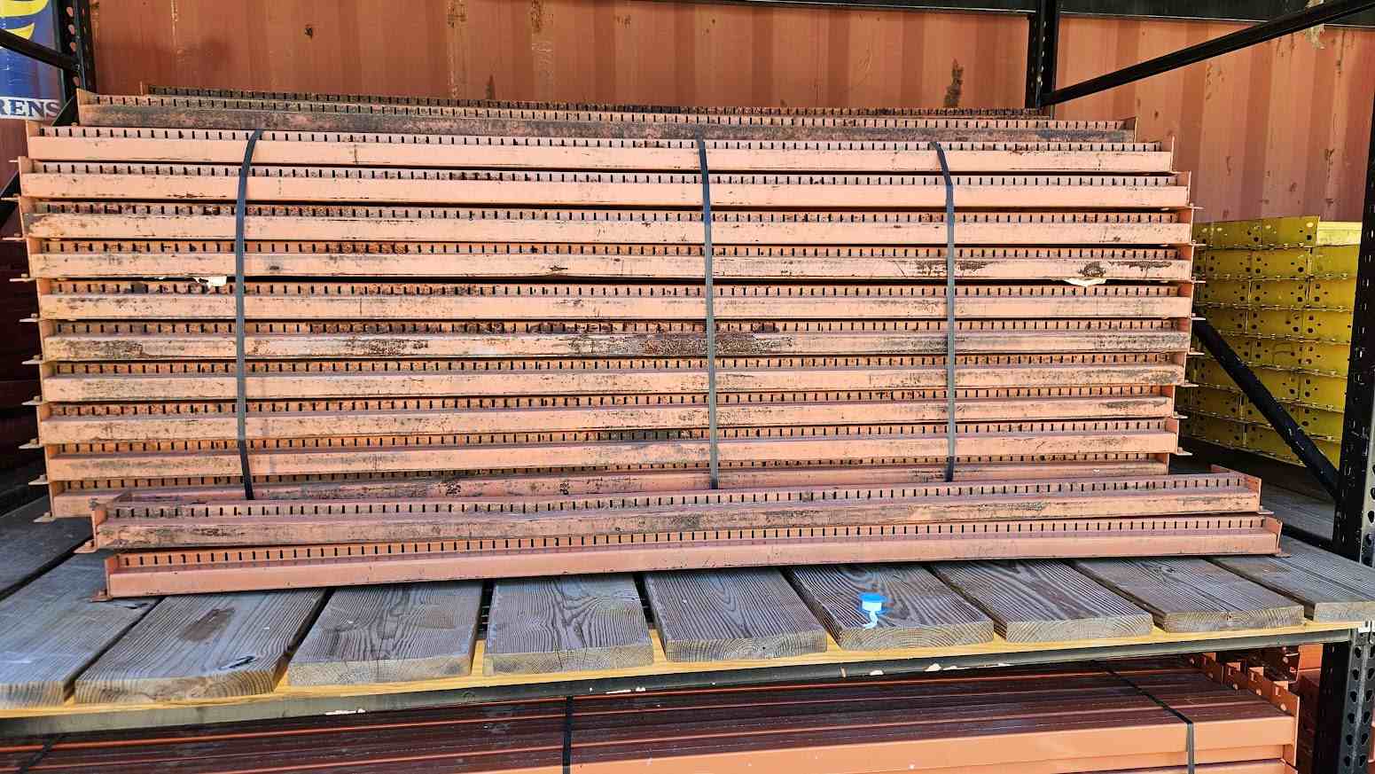 A large bundle of 93-inch industrial teardrop pallet rack step beams in used condition, secured with black banding on a wooden pallet and showing a standard 3-inch face height for heavy-duty warehouse storage applications.
