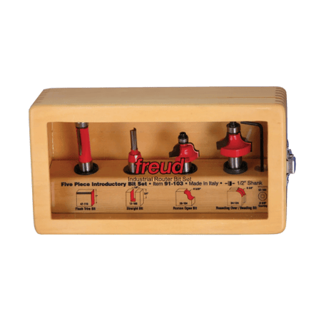 Image of bit set in closed wooden case. The image shows a light-colored wooden case with a clear plastic window, displaying a Freud five-piece introductory router bit set. Inside, five router bits with red shanks and various cutting head shapes are neatly arranged in individual slots.