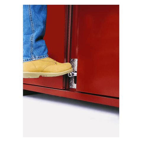 Close up of foot latch. This is a close-up shot of a person's foot stepping onto a red metal surface. The person is wearing blue jeans and a light brown shoe, and a silver metal component is visible at the bottom of the red surface.