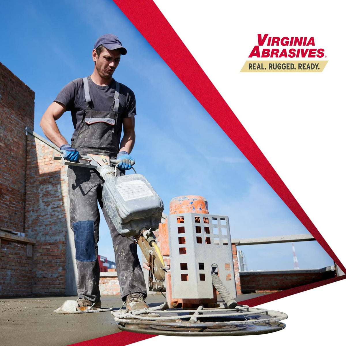 A construction worker operates a walk-behind power trowel to smooth a concrete slab on a job site with a brick wall in the background.