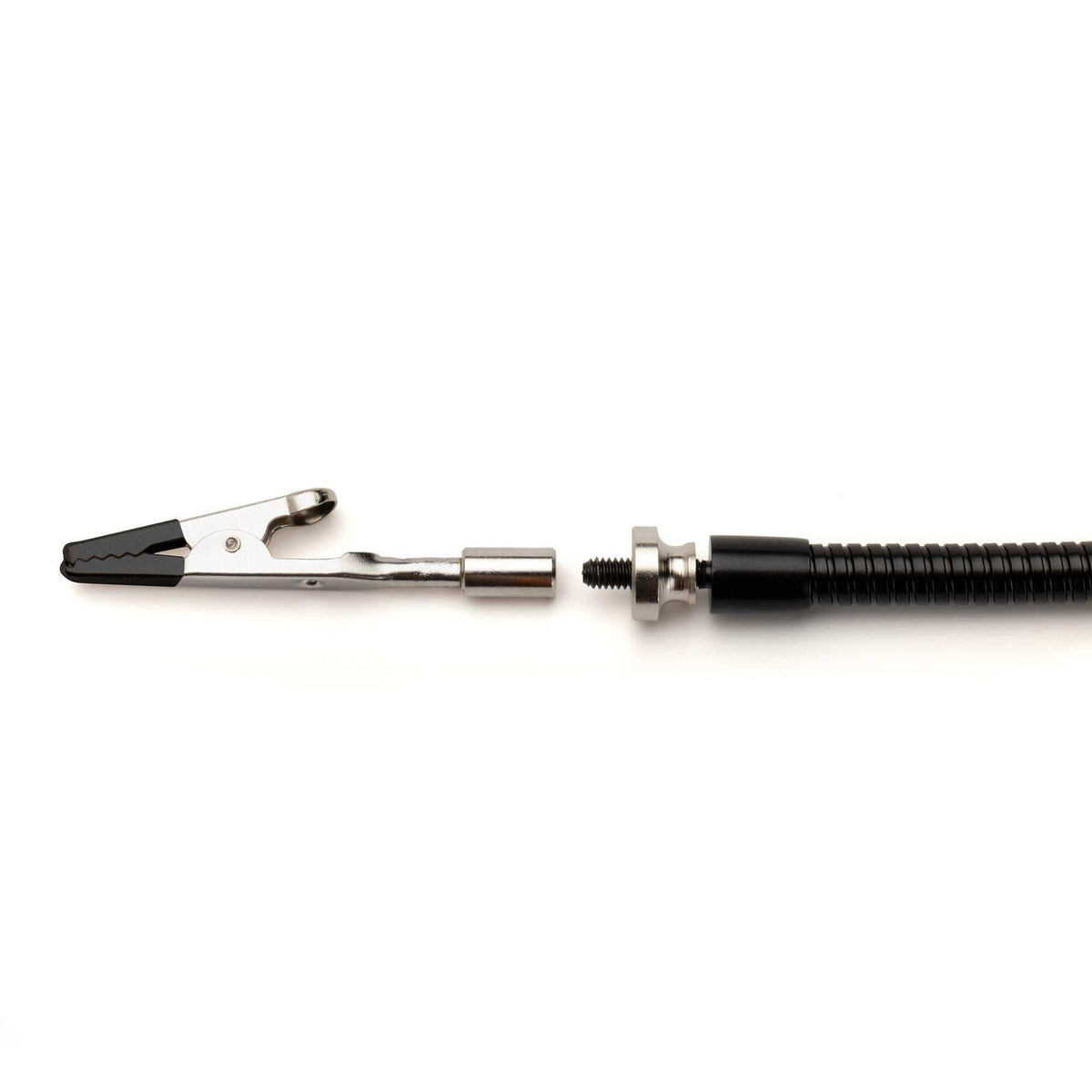 Close-up of alligator clip attached to metal connector and flexible conduit, used in electronics assembly.