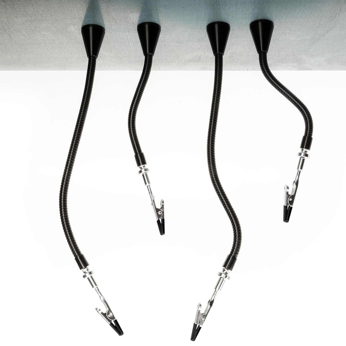 Four flexible gooseneck arms with clips mounted to workbench edge, used for holding components during soldering.