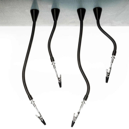 Four flexible gooseneck arms with clips mounted to workbench edge, used for holding components during soldering.
