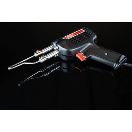 A high-contrast shot of the Weller D550 soldering gun resting on a reflective black surface, emphasizing the professional build quality and sleek industrial design of the dual-heat tool.