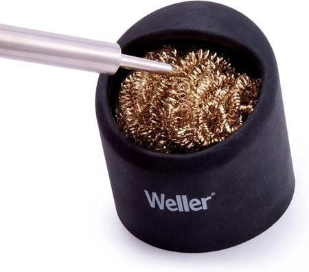 A close-up view of a soldering iron tip being plunged into the brass wire coils of the Weller dry tip cleaner to effectively remove residue and oxidation without thermal shock.