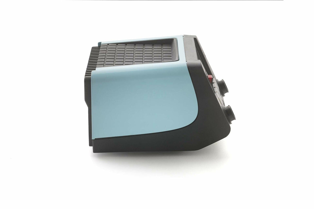 Side view of a vintage electronic device with light blue panel, black base, and grid-patterned top. Front panel includes knobs and buttons. Design suggests mid-20th century origin, possibly a typewriter or early terminal.
