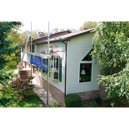 Distance view of a construction worker installing siding on a house while standing on a walk plank supported by two Werner pump jack poles.