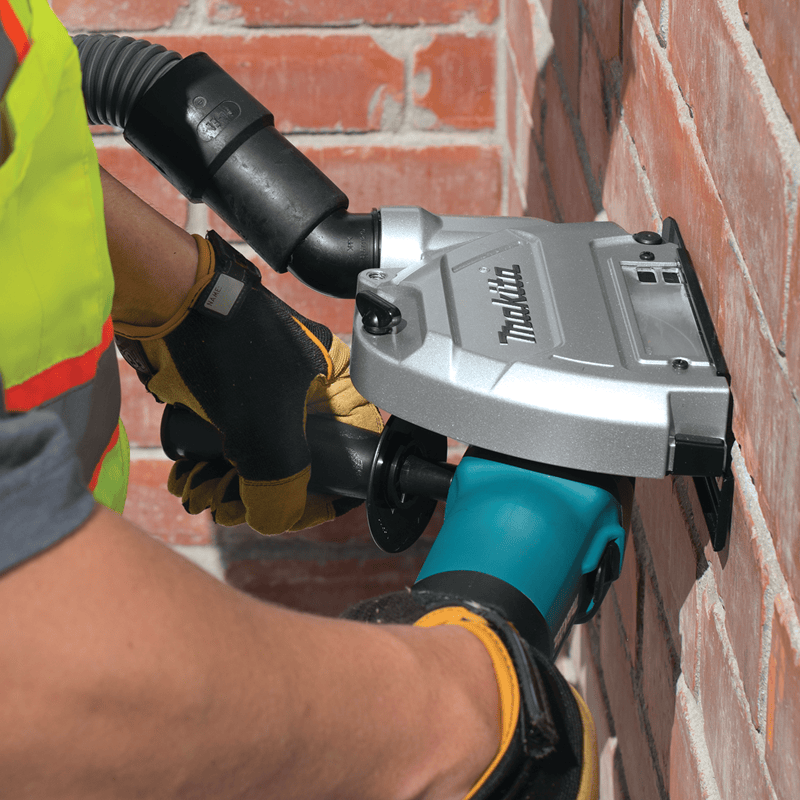 Person using a Makita angle grinder on a brick wall