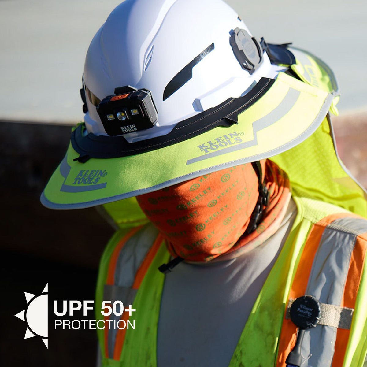Person wearing a high-visibility safety vest and helmet with UPF 50+ protection label.