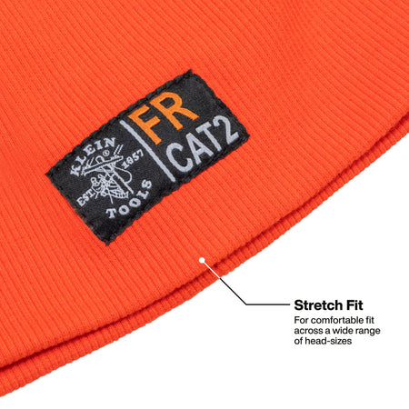 Close-up of a bright orange ribbed knit beanie with a black sewn-in patch reading Klein Cat 2, plus a callout line and text noting stretch fit across a wide range of head sizes.