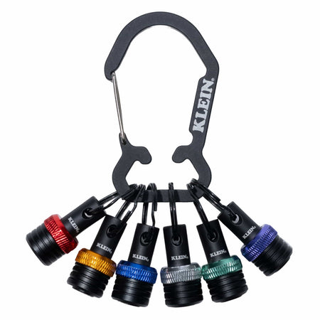 A set of six small black cylindrical accessories attached to a black carabiner with the brand name KLEIN visible on the carabiner and on the accessories. The set includes different colored rings at the ends: red, gold, blue, silver, green, and purple-blue.