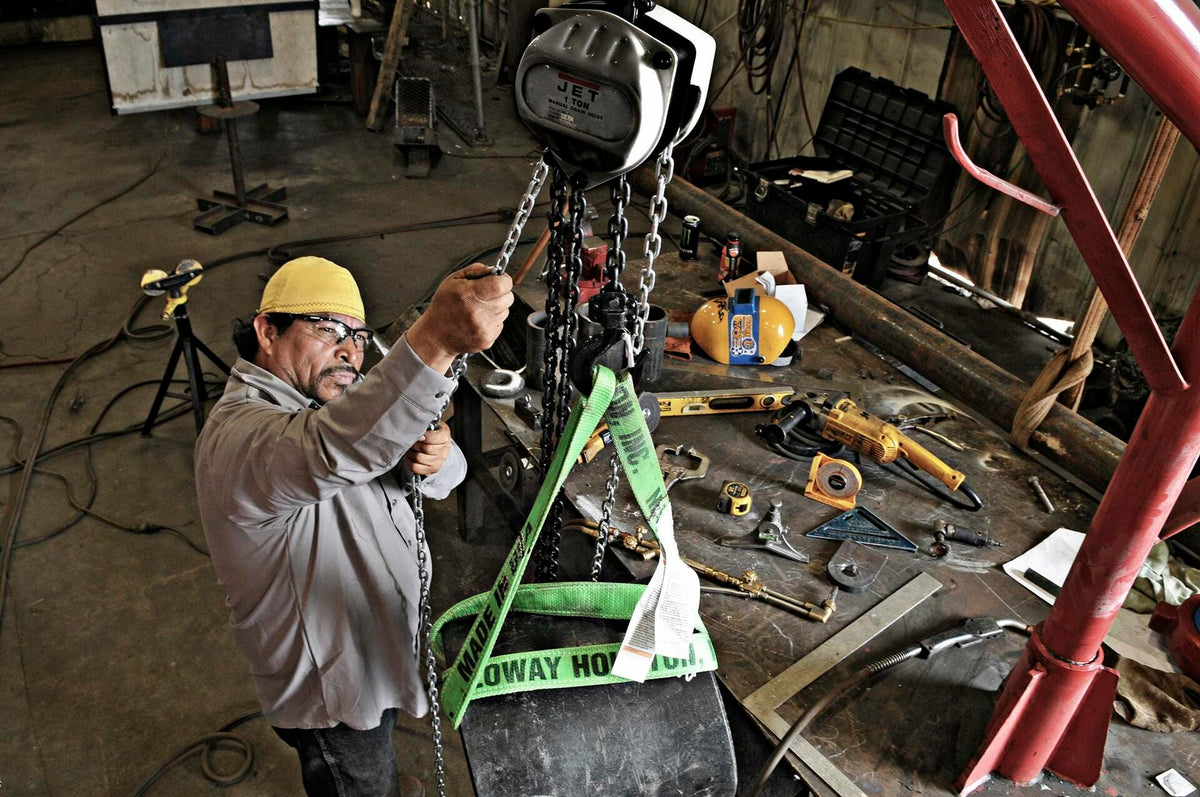 Person using a crane in a workshop with tools and equipment around