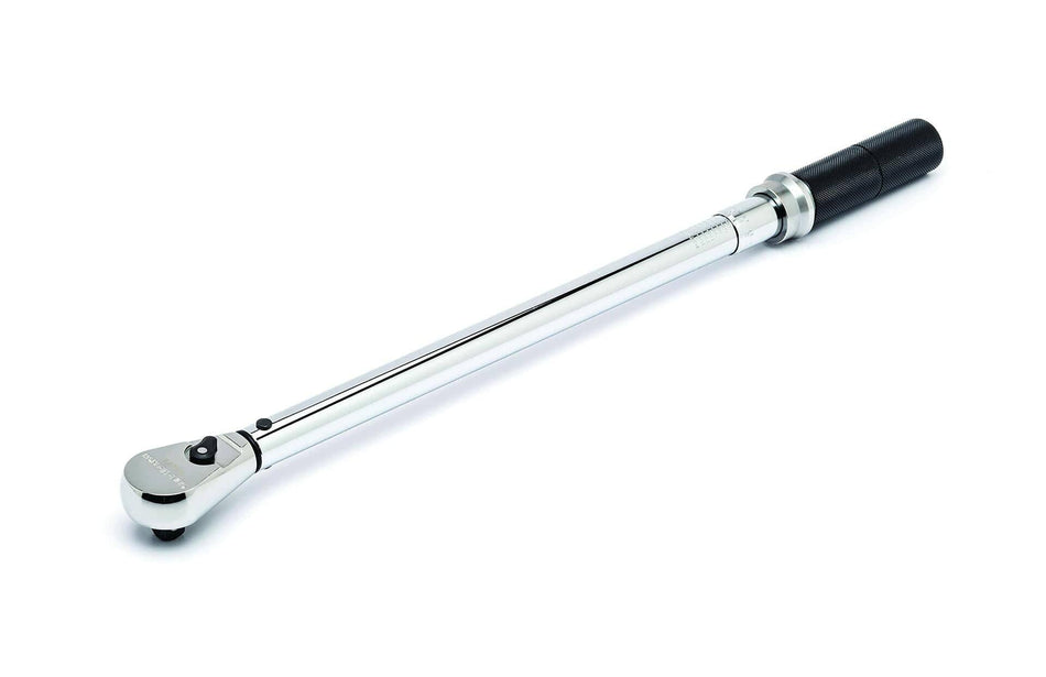This image displays a chrome-plated torque wrench positioned diagonally, pointing from the lower left to the upper right against a white background. The right end features a black, textured handle, and the left end has a silver ratchet head with a small black lever.