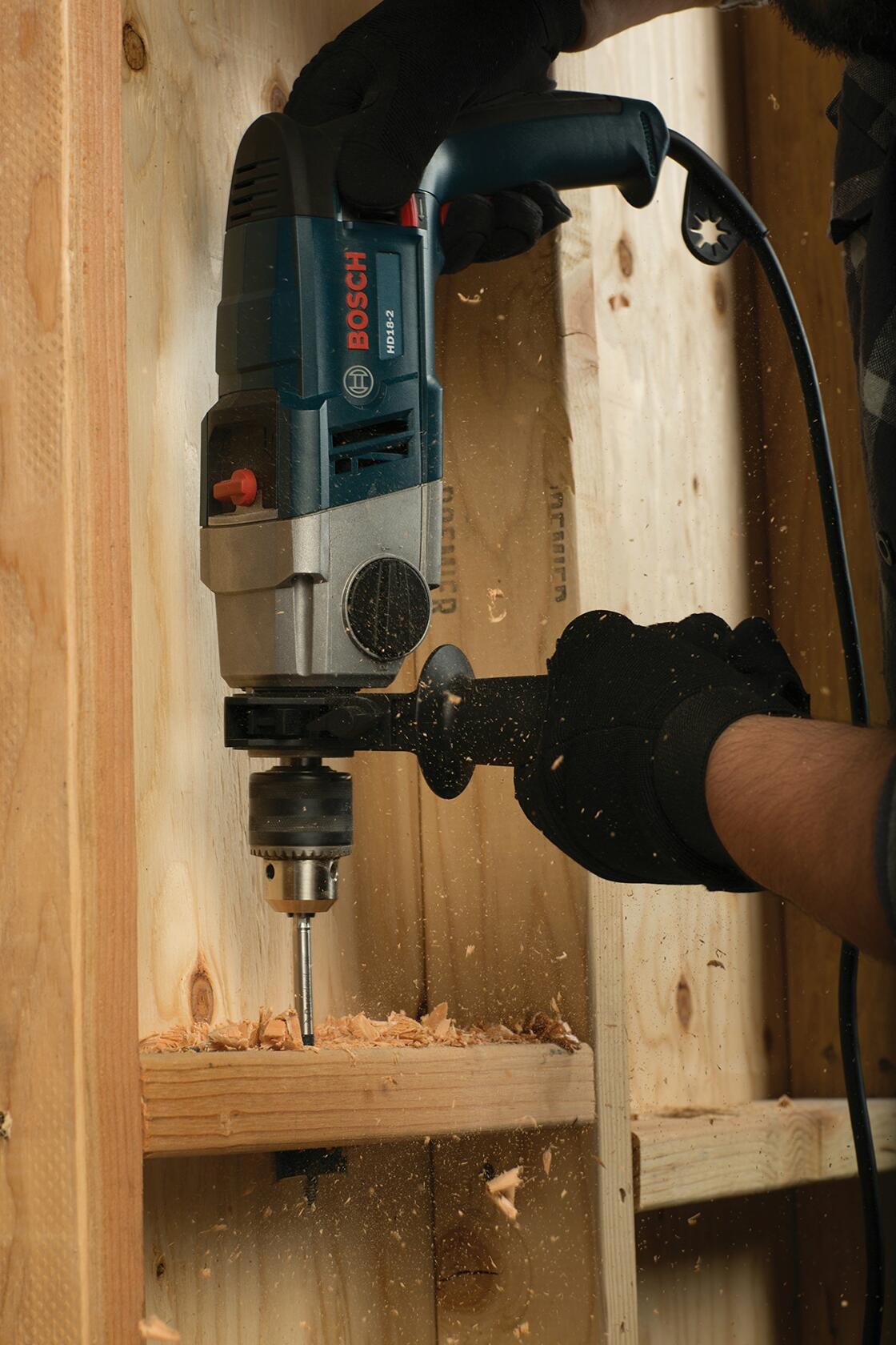Bosch HD182RT 8.5 Amp 1/2 in. Two-Speed Hammer Drill in use with wood drilling and dust particles visible