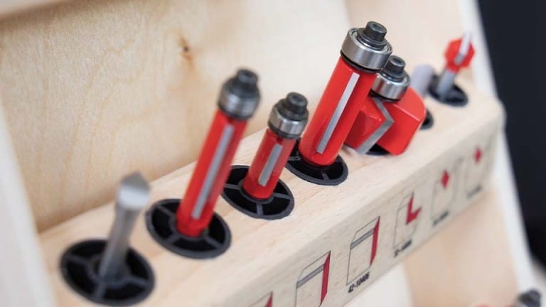 Load video: Red and black sewing machine needles on a wooden holder with measurement markings.