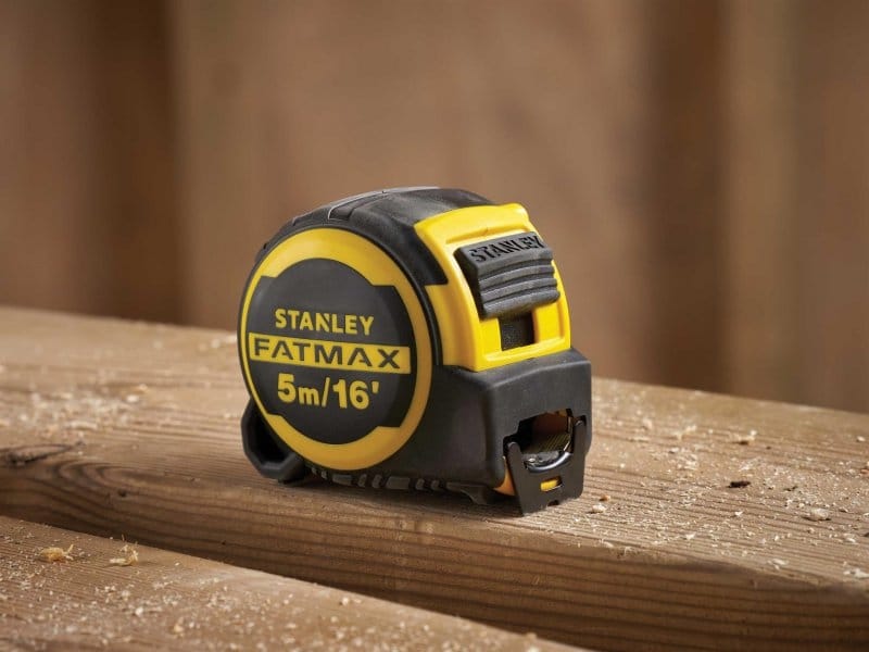 Load video: Stanley FatMax tape measure on a wooden surface with a blurred background