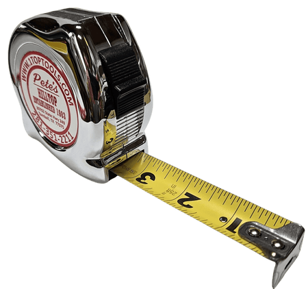 Angled view of the chrome tape measure with the 1 inch wide yellow blade partially extended, showing high visibility SAE scale markings and the thumb lock mechanism.