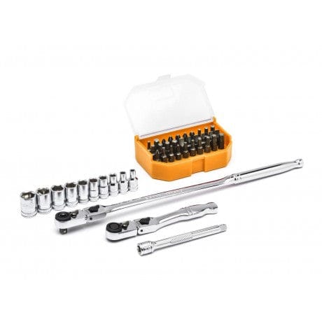 This is a photograph showing an assortment of tools laid out on a white surface. The tools include metal sockets, several silver ratchets, and a yellow and orange container filled with small bits.
